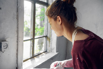 Portrait of young woman looking through window