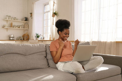Young woman using laptop while sitting on sofa
