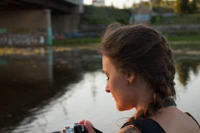 Looking at her camera photographer girl of slavic appearance with braided brown hair in the sunset