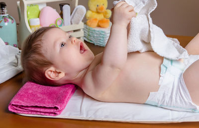 Cute baby girl holding napkin while lying down at home