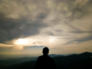 Silhouette man standing on mountain against sky during sunset