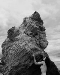 Low angle view of woman on rock against sky