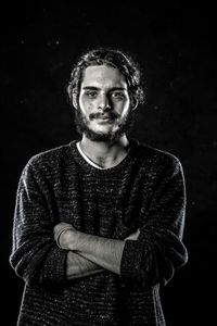 Portrait of smiling young man against black background