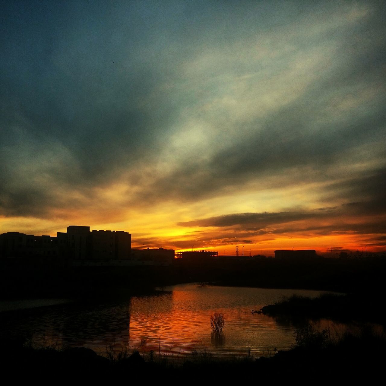 sunset, water, silhouette, sky, orange color, scenics, beauty in nature, tranquil scene, cloud - sky, tranquility, reflection, lake, idyllic, nature, cloud, building exterior, river, built structure, waterfront, dramatic sky