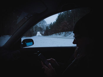 Man seen through car windshield during winter