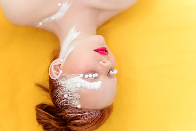Portrait of a young woman in white creative makeup on a yellow background