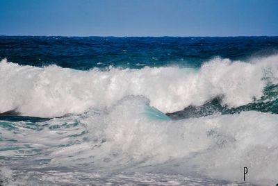 Waves splashing in sea against sky