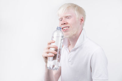 Man with albino holding water bottle against white background