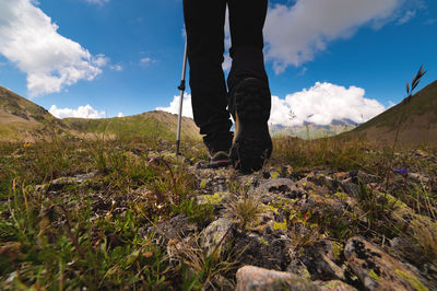 Hiking trail with flowers, green grass and stones. close up of hiking boots in the mountains against