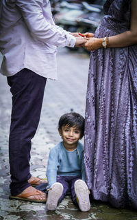 Rear view of couple standing holding hands and son son sitting between them 