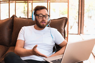 Woman using laptop while sitting on sofa at home