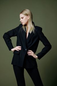 Portrait of young woman standing against black background