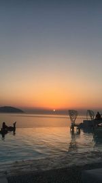 Silhouette boats in sea against dramatic sky during sunset