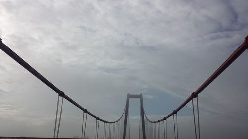 Low angle view of crane against cloudy sky