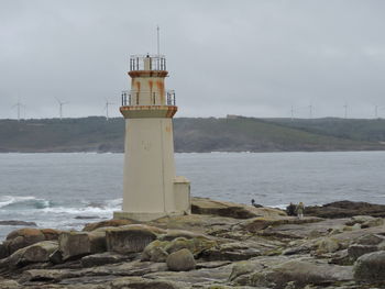 Lighthouse by sea against sky