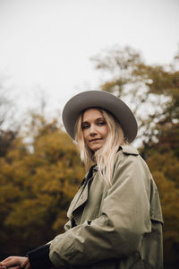 Portrait of smiling young woman against trees