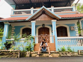 Rear view of woman sitting in front of building