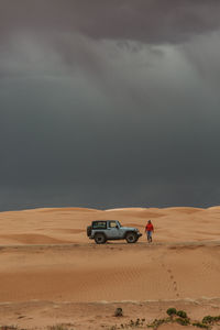 Woman tourist gets out of jeep in the stormy sand dunes of utah