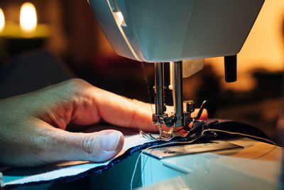 Cropped hands using sewing machine in darkroom