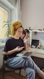 Woman wearing a yellow towel on her head working at her home office surrounded with two children