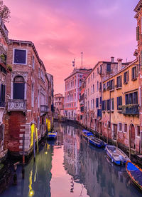 Canal amidst buildings in city against sky