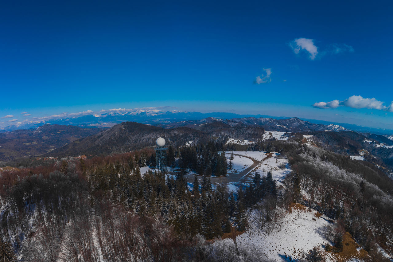 SCENIC VIEW OF TREES AND MOUNTAINS AGAINST BLUE SKY