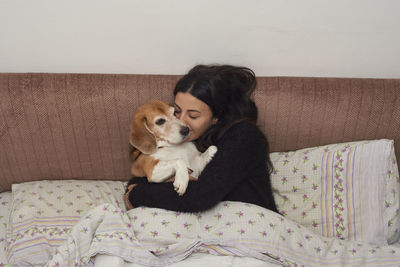 Portrait of young woman sitting on bed at home