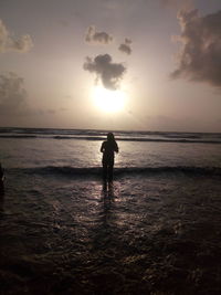 Silhouette man standing on beach against sky during sunset