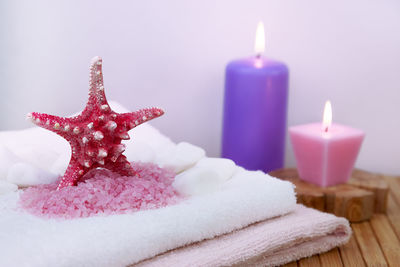 Close-up of burning candles and starfish on towels