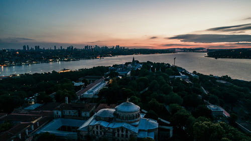 High angle view of city by sea against sky at sunset