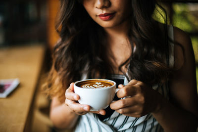 Midsection of woman holding coffee cup in cafe