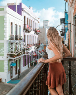 Woman standing by railing while looking outdoors