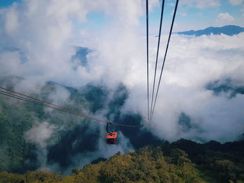 Overhead cable car over mountains against sky