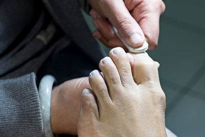 Midsection of woman cleaning customer toe nails