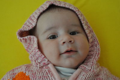 Cute baby girl wearing knitted warm clothing lying on bed