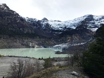 Scenic view of river by mountains against sky