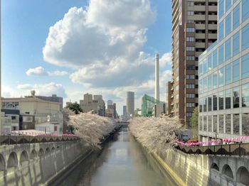 Canal amidst buildings in city against sky