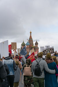 Rear view of people outside temple against sky