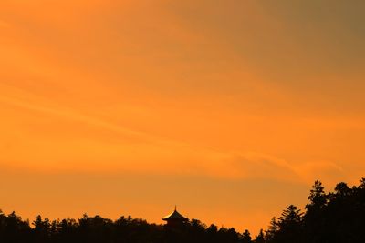 Silhouette trees against orange sky