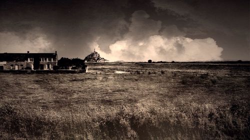 View of field against cloudy sky