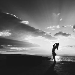 Side view of silhouette woman with arms raised on beach