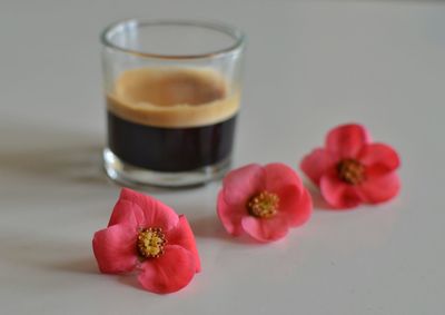 Close-up of pink flowers by coffee on table