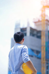 Rear view of boy standing against built structure
