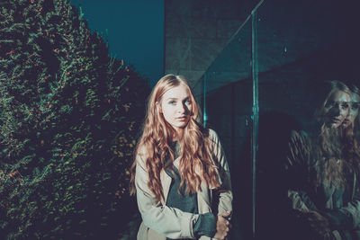 Portrait of young woman standing by window