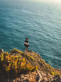 Rear view of man standing on rock by sea