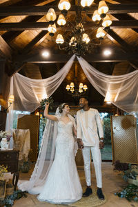 Smiling woman with bouquet holding hand on man while standing at banquet