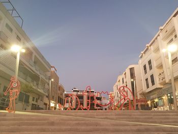 Illuminated city street against clear sky at night