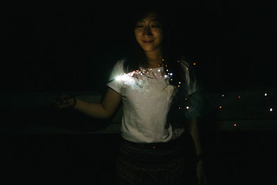 Woman holding illuminated light painting at night