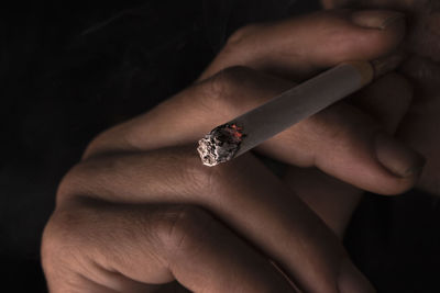 Cropped image of man smoking cigarette against black background