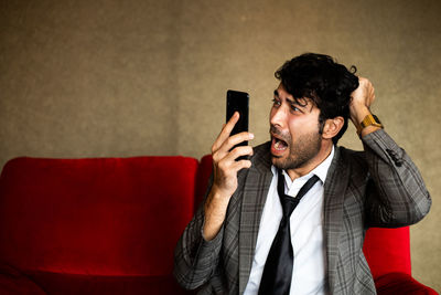 Young man using mobile phone on sofa